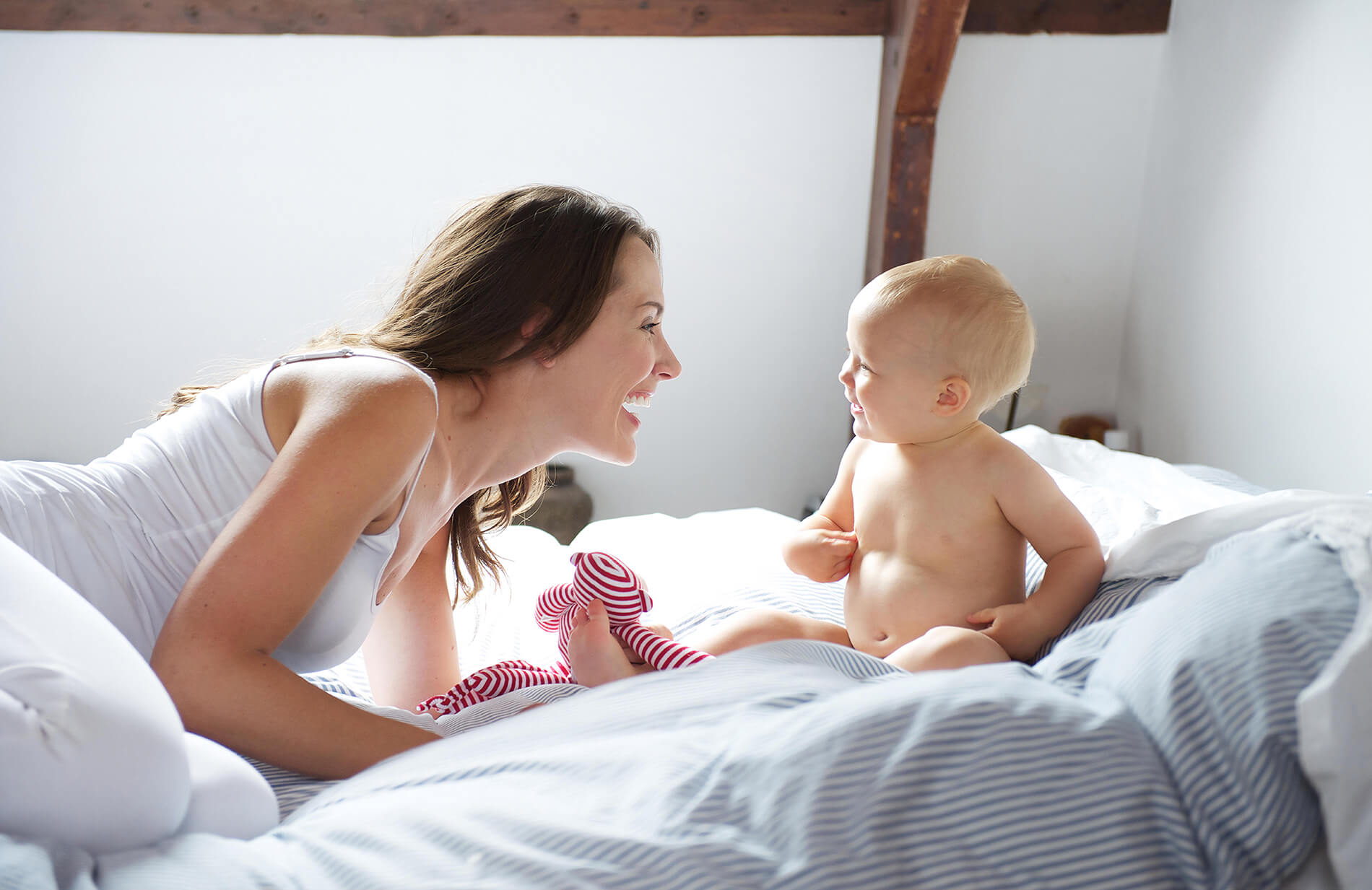 Photo of a happy mother and baby playing on a bed